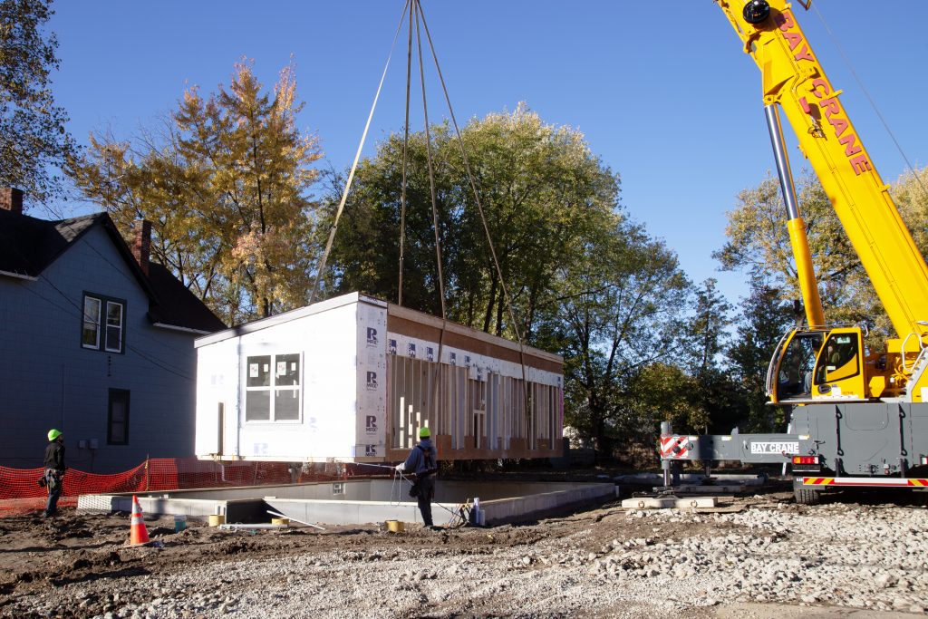 A section of a Habitat modular home is lowered in place.